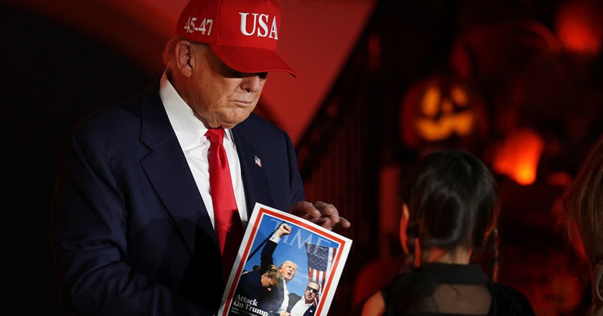 President Donald Trump signs a copy of a Time magazine cover as he and first lady Melania Trump hand out candy to children during the annual Halloween event at White House on October 30, 2025 (Getty Images)