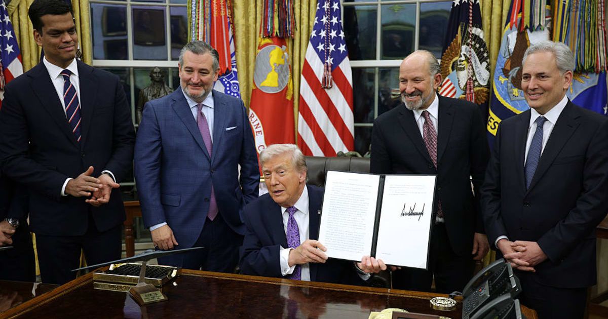 Trump displays a signed executive order as (2nd L-R) US Sen Ted Cruz, Commerce Secretary Howard Lutnick and White House artificial intelligence (AI) and crypto czar David Sacks look on in the Oval Office on December 11, 2025 (Getty Images) 