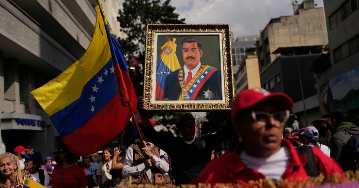 A government supporter holds an image of President Nicolas Maduro during a women's march to demand his return to Caracas, Venezuela, Tuesday, January 6, 2026, three days after US forces captured him and his wife (AP Photo/Matias Delacroix)