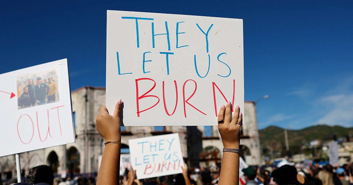 Demonstrators hold signs at the 'They Let Us Burn!' rally on the first anniversary of the Palisades Fire on January 07, 2026 in Pacific Palisades, California January 7, 2026, marks the first anniversary of the devastating Los Angeles fires (Getty Images)