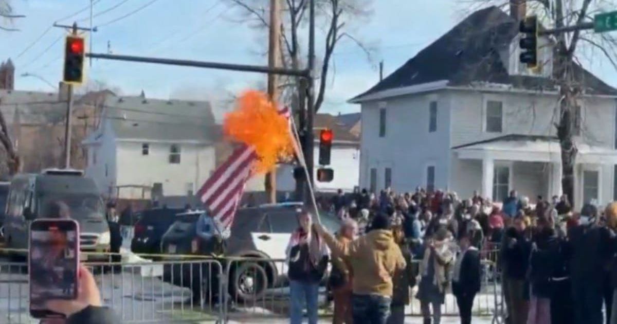 American flag burned during Minneapolis protests after ICE shoots, kills woman (@RT_com/X)
