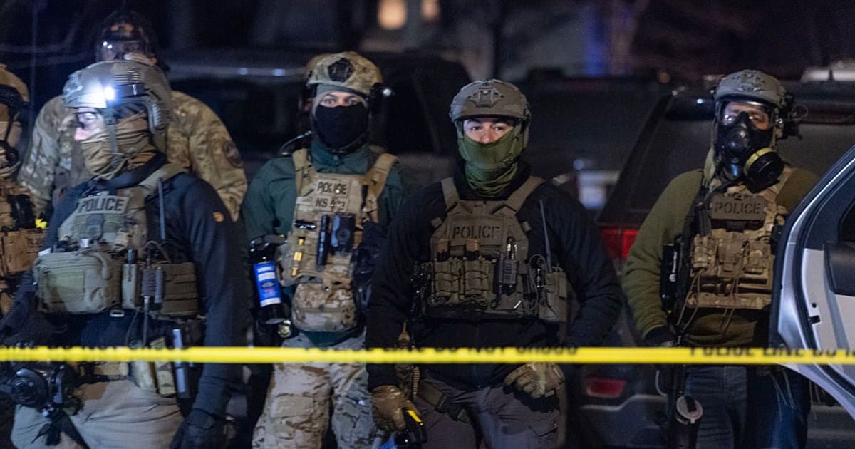 Federal agents guard a perimeter following a shooting incident as angry residents protest their presence in the city on January 14, 2026, in Minneapolis (Scott Olson/Getty Images)