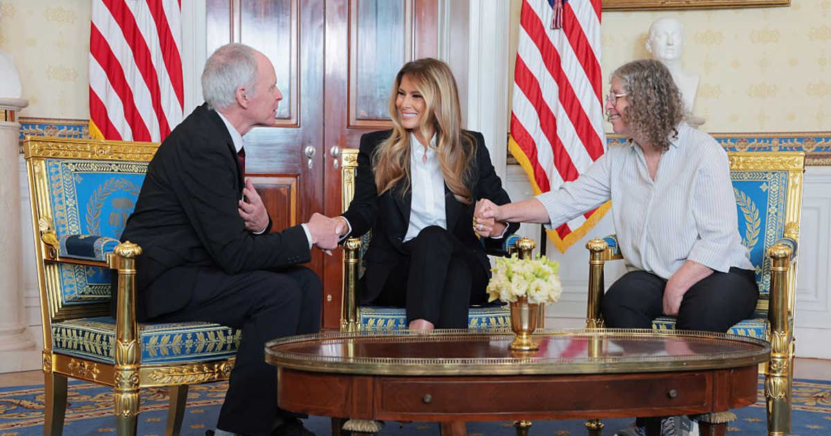 First lady Melania Trump, Keith Siegel (L) and Aviva Siegel (R) holds hands during a meeting in the Blue Room of the White House on February 04, 2026 in Washington, DC (Anna Moneymaker/Getty Images)