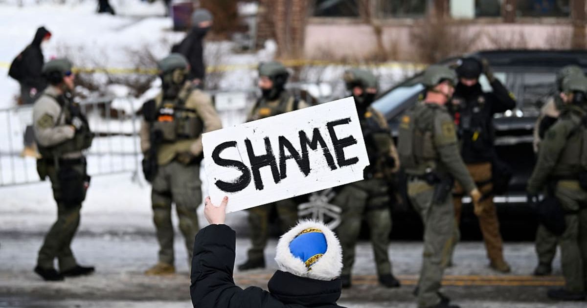 An onlooker holds a 'Shame' sign as law enforcement responds to a suspected ICE agent shooting on January 7, 2026, in Minneapolis, Minnesota (Stephen Maturen/Getty Images)