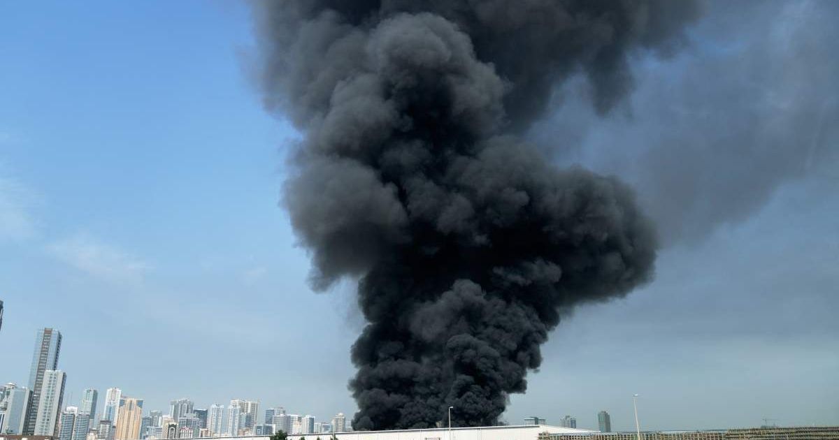 A black plume of smoke rises from a warehouse in the industrial area of Sharjah City, United Arab Emirates, Sunday, March 1, 2026, following reports of Iranian strikes in Dubai (AP Photo/Altaf Qadri)