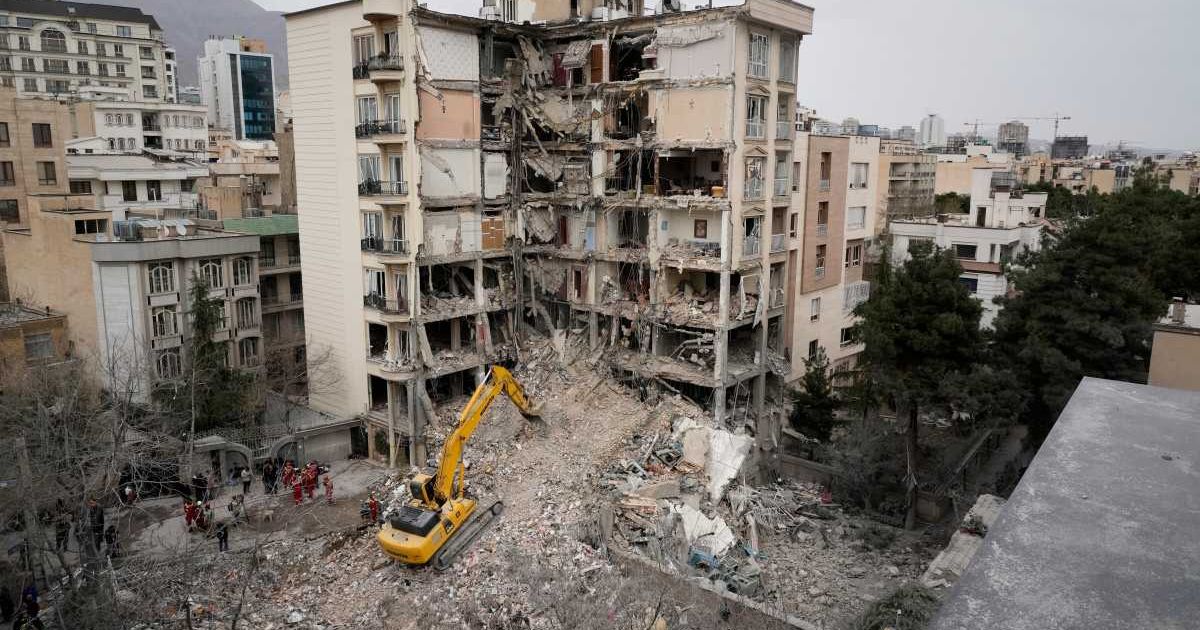 Iranian Red Crescent emergency workers use a bulldozer to clear rubble from a residential building that was hit in an earlier US-Israeli strike in Tehran, Iran, Monday, March 23, 2026. (AP Photo/Vahid Salemi)