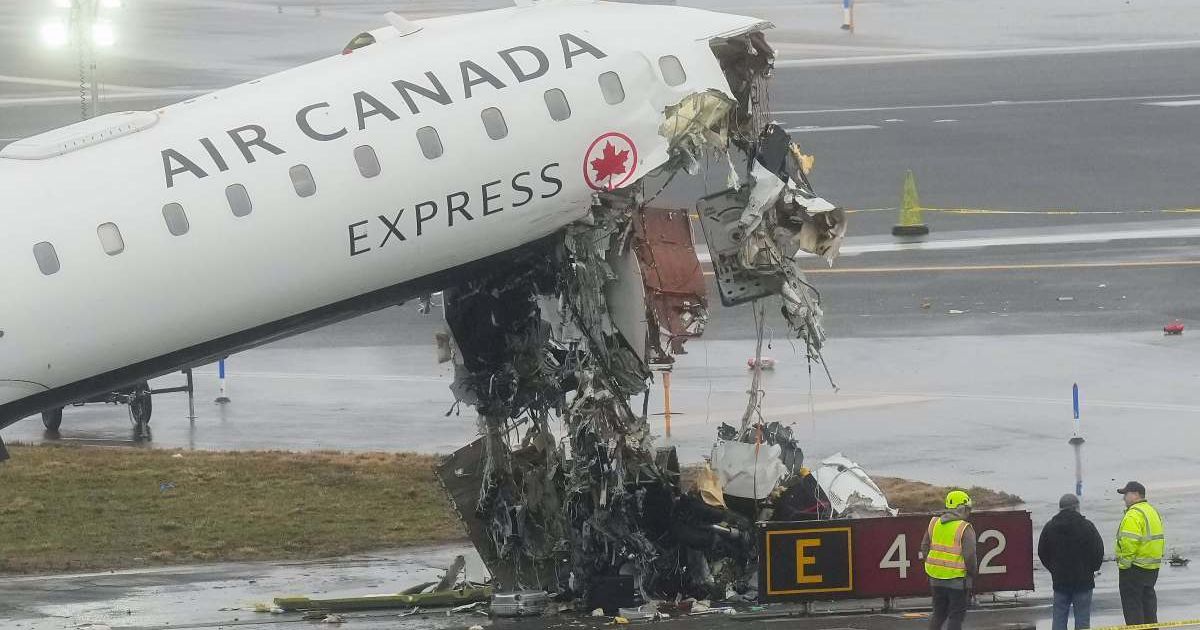 Officials investigate the site, Monday, March 23, 2026, where an Air Canada jet came to rest after colliding with a Port Authority firetruck at LaGuardia Airport, shortly after landing Sunday night in New York (AP Photo/Seth Wenig)