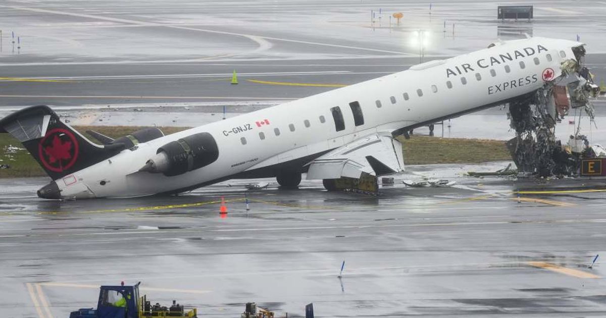 Investigators walk the site, Monday, March 23, 2026, where an Air Canada jet came to rest after colliding with a Port Authority fire truck at LaGuardia Airport (AP Photo/Seth Wenig)