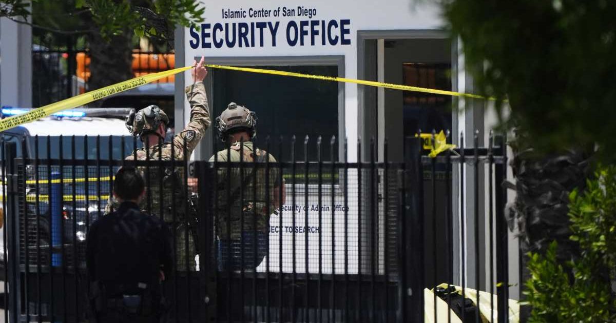 A body is covered with a tarp at the scene of a shooting outside the Islamic Center of San Diego, Monday, May 18, 2026, in San Diego (AP Photo/Gregory Bull)

