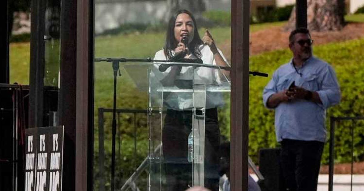Rep Alexandria Ocasio-Cortez (D-NY) speaks from behind a bullet-resistant glass during a voting rights rally on Saturday, May 16, 2026, in Montgomery, Alabama (AP Photo/Mike Stewart)