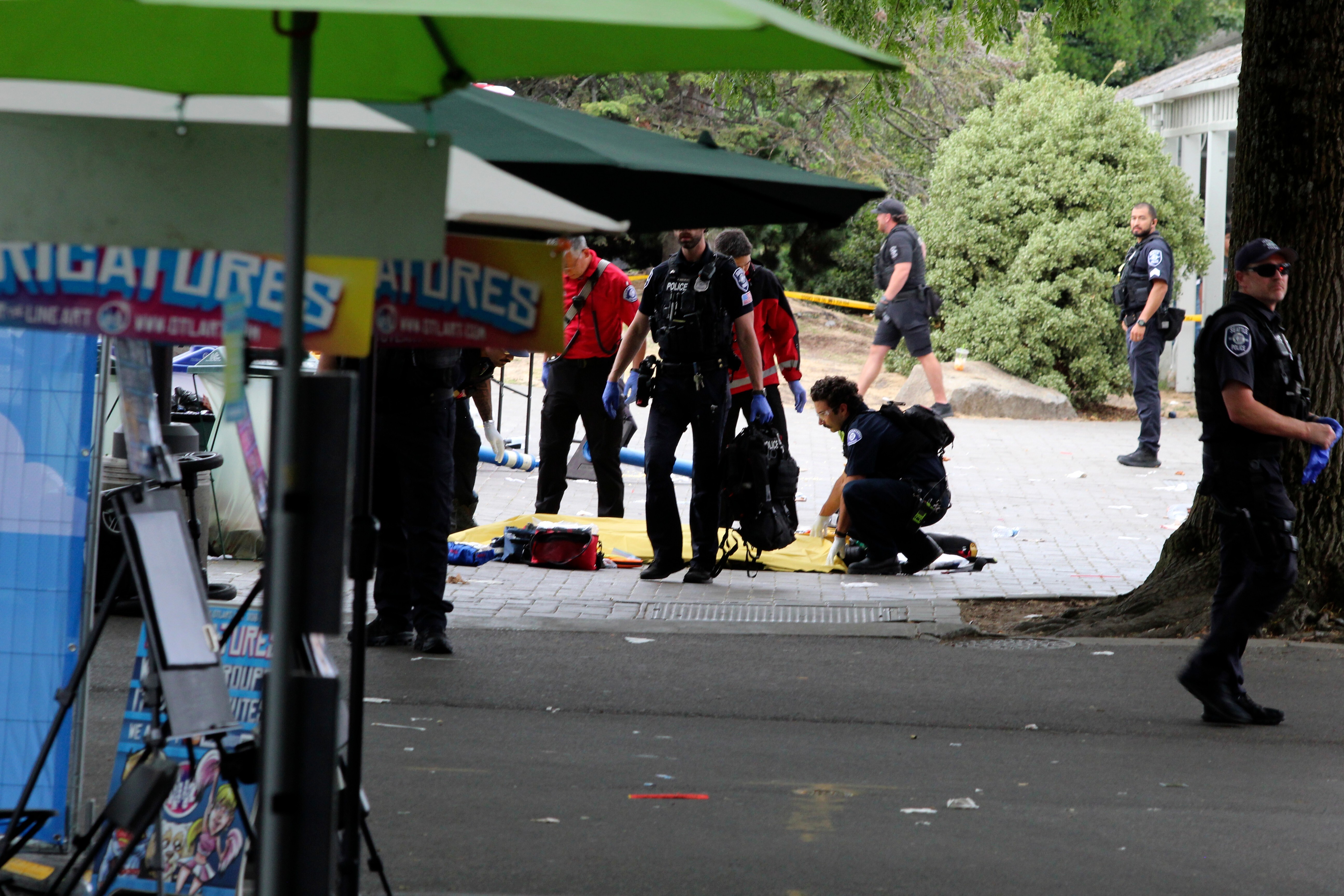 Police cover a person after a shooting at Seattle Center during the Bite of Seattle food festival Sunday, July 26, 2026, in Seattle, Wash.
