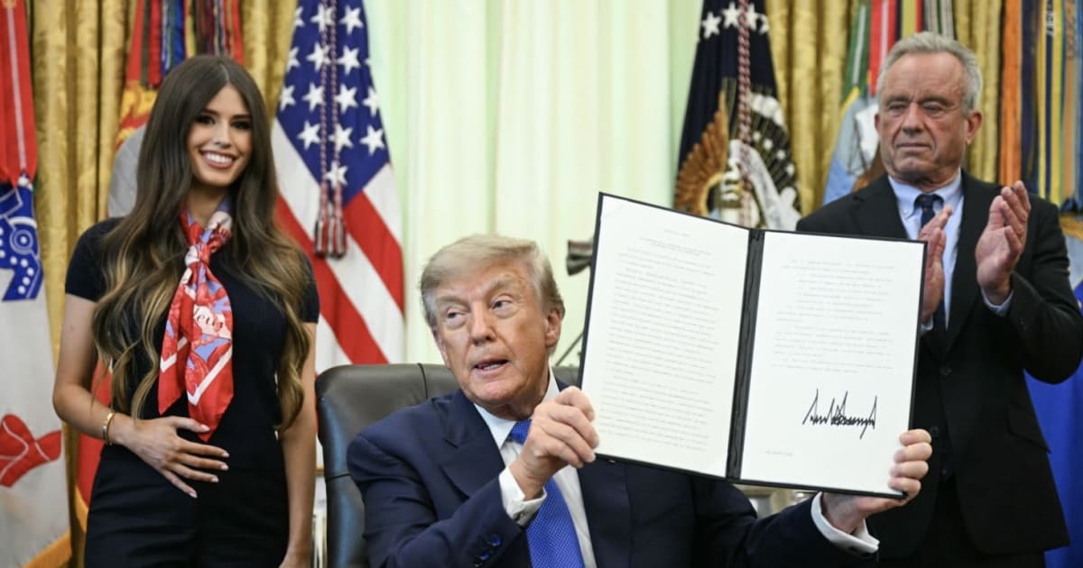 A woman behind President Donald Trump at a White House signing drew online attention after footage showed her standing with a hand on her stomach (@jaymefranklin16/X)