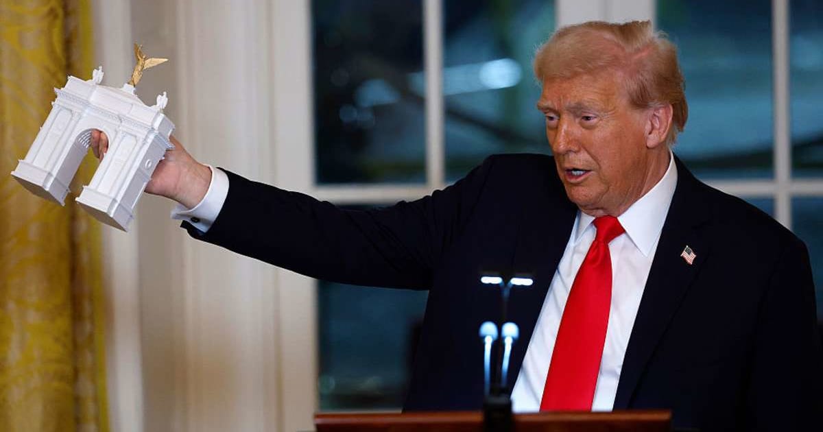 President Donald Trump holds a model of an arch as he delivers remarks during a ballroom fundraising dinner in the East Room of the White House on October 15, 2025, in Washington, DC (Getty Images)