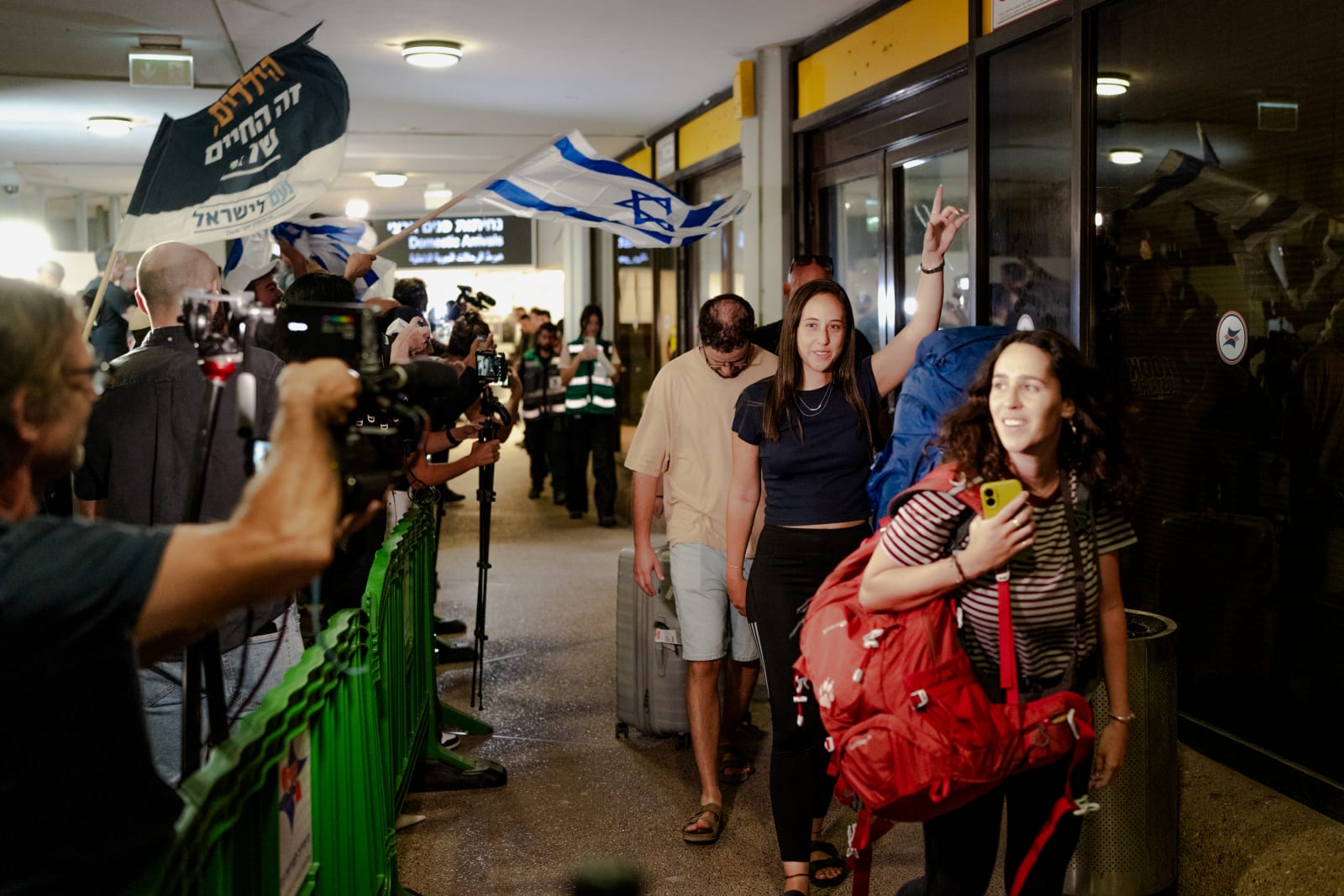 assengers carry luggage through the terminal corridor lined with waiting crowds and flags upon arriving on a Flydubai retrieval flight at Ben Gurion Airport on September 30, 2026 in Tzafria, Israel (Erik Marmor/Getty Images)